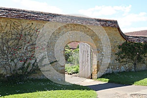 An arched gateway with an old wooden door leads in to the kitchen garden in an old English country manor house