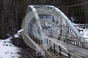 An arched metal bridge over the river in winter time