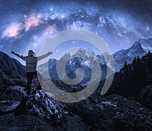 Arched Milky Way and sporty man on the stone and mountains