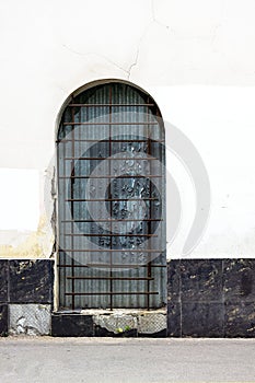The arched passage in the wall an opening in the old style is closed with a metal grating made of rebar