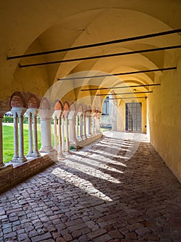 Arched porch with white stone columns in the courtyard of a Benedictine abbey.