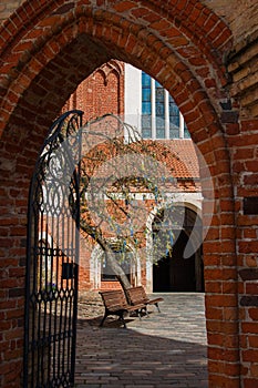 Arched red-brick entrance to the church with a tree inside the courtyard