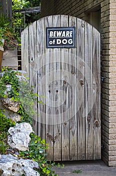 Arched rustic wooden door to steps and garden with Beware of Dog sign