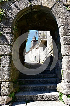 Arched stone door in medieval wall with church view. Ribadavia, Spain.