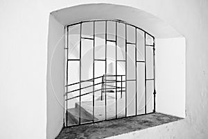 Arched window with metal grating. Black and white