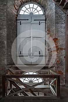 Arched window on an old brick wall, closed by wooden shutters