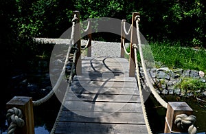 Arched wooden bridge in the park. the railing posts are connected by a strong jute rope. Knots finished with a rope work of a Japa