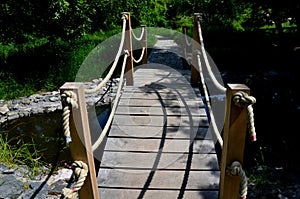 Arched wooden bridge in the park. the railing posts are connected by a strong jute rope. Knots finished with a rope work of a Japa