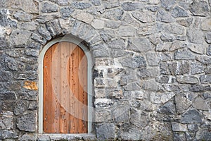 Arched wooden door in natural stone wall