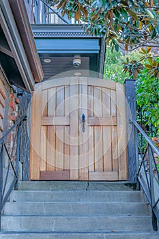 Arched wooden double gate entrance with concrete stairs and security camera- San Francisco, CA