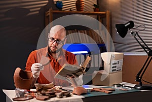 Archeologist working late night in office studying with book