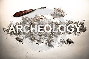 Archeology word written in letters on a pile of ash, dirt, soil, ground as excavation of history artifact concept background. Sea