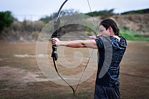 Archer aiming at his target at a shooting range outside.