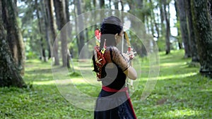 Archery woman hunting an enemy inside the forest with an arrow and a bow