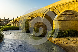 The arches and buttresses of the Roman bridge of Cordoba, Spain illuminated by the evening sun