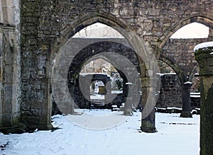 Arches and columns in the ruined medieval church in hebden bridge west yorkshire with snow covering the ground in winter