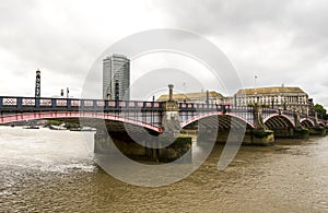 Arches of Lambeth bridge and brown waters of river Thames flowing through, London, England