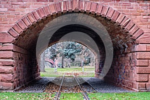 the arches in an old brick structure allow a view into an empty field