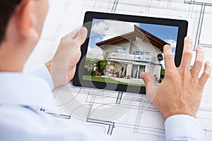 Architect analyzing house on digital tablet over b