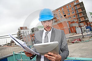 Architect with bluprint on building site