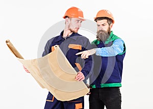 Architect and build concept. Men in helmets with blueprint