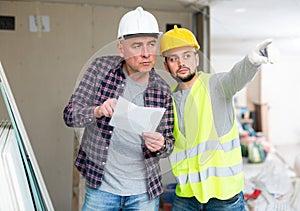 Architect and builder discussing documentation in construction site