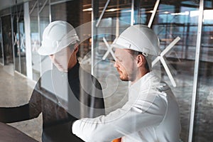 Architect and builder lookin on blueprint building under construction photo