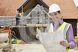 Architect On Building Site Looking At House Plans