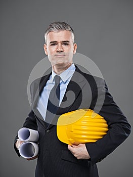 Architect carrying blueprints and hardhat