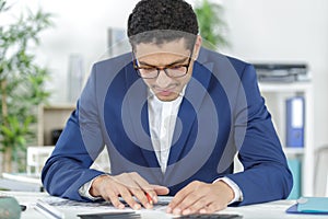 architect in casualwear sitting by table reading project photo