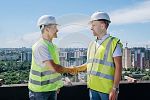 Architect and civil engineer shaking hands on the construction site.