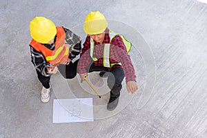 Architect and client discuss help create plan with blueprint of the building at construction site floor