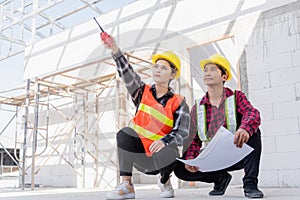 Architect and client discussing help create plan with blueprint of the building at construction site