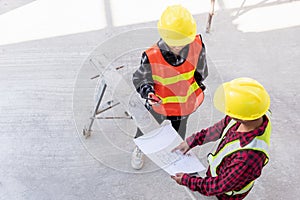 Architect and client discussing help create plan with blueprint of the building at construction site floor