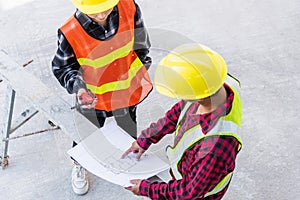 Architect and client discussing help create plan with blueprint of the building at construction site floor