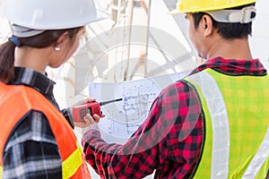 Architect and client discussing the plan with blueprint of the building at construction site