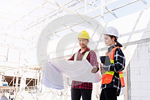 Architect and client discussing the plan with blueprint of the building at construction site