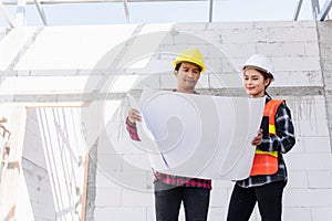 Architect and client discussing the plan with blueprint of the building at construction site