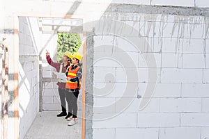 Architect and client discussing the plan with blueprint of the building at construction site