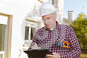 Architect with clipboard in hardhat at construction site
