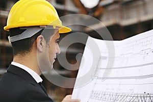 Architect in construction site looking at building plans