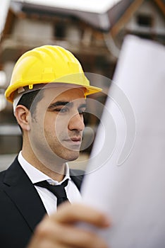 Architect in construction site looking at building plans