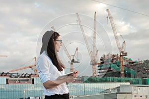 Architect on the construction site makes supervision. Young female engineer with tablet computer in hand.