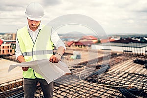 architect on construction site with plans and hardhat. vintage filter edit