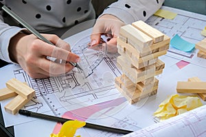 Architect designer Interior creative working hand playing a block wood game on desk architectural plan of the house, a