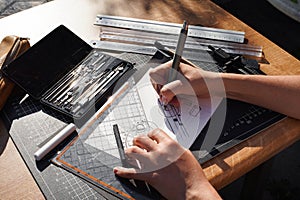 Architect and designer working accurately on a project drawing sketches and technical drafts on paper using professional tools