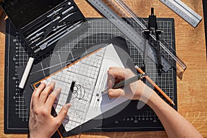 Architect and designer working accurately on a project drawing sketches and technical drafts on paper using professional tools