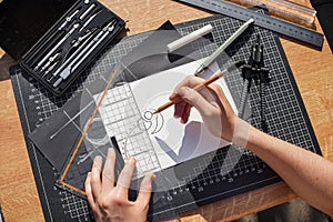 Architect and designer working accurately on a project drawing sketches and technical drafts on paper using professional tools
