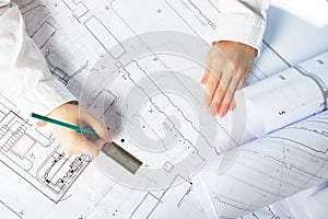 Architect designer working on architectural blueprints, building plans in the office, drawing