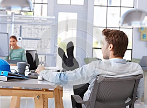 Architect designing with computer feet up on desk